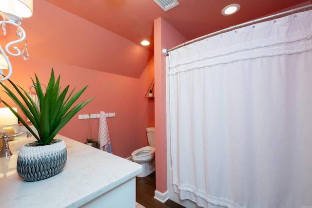 bathroom with wood-type flooring, lofted ceiling, and toilet