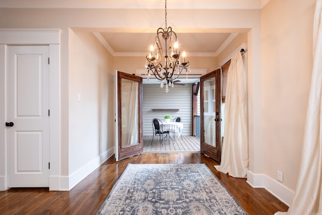 hall with dark hardwood / wood-style floors, french doors, ornamental molding, and an inviting chandelier