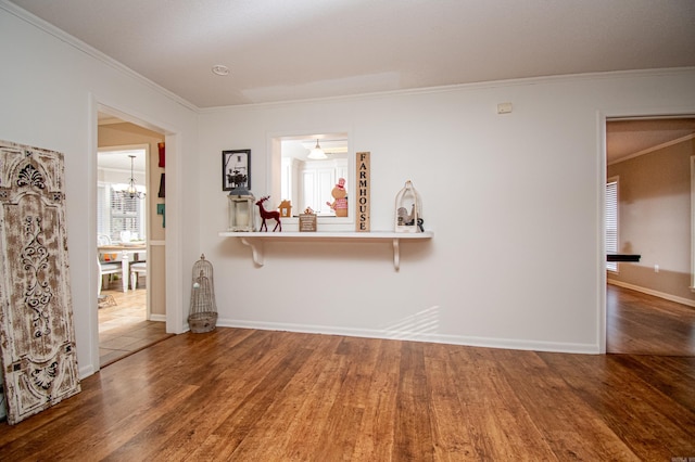 unfurnished living room featuring a notable chandelier, wood-type flooring, and crown molding