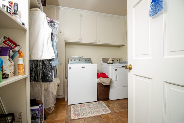 clothes washing area with washer and dryer, light tile patterned flooring, and cabinets