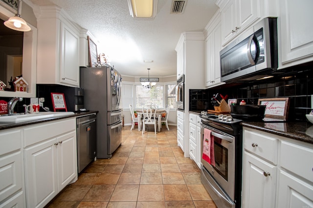 kitchen featuring white cabinets, hanging light fixtures, ornamental molding, appliances with stainless steel finishes, and light tile patterned flooring