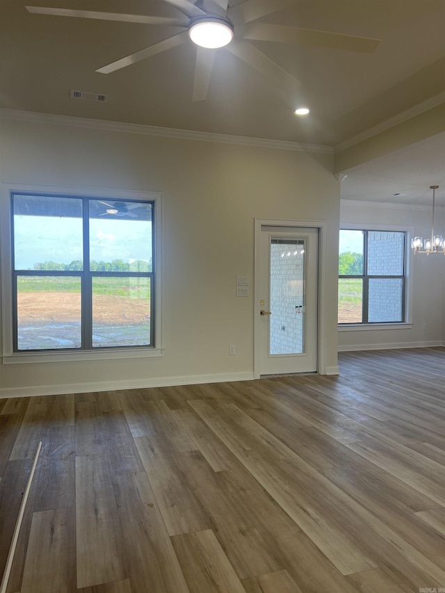unfurnished room featuring wood finished floors, ornamental molding, ceiling fan with notable chandelier, baseboards, and visible vents