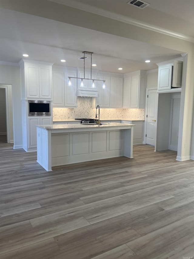 kitchen with tasteful backsplash, white cabinets, ornamental molding, and custom exhaust hood