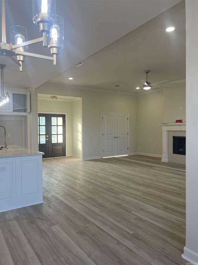 unfurnished living room with baseboards, recessed lighting, a fireplace, wood finished floors, and ceiling fan with notable chandelier