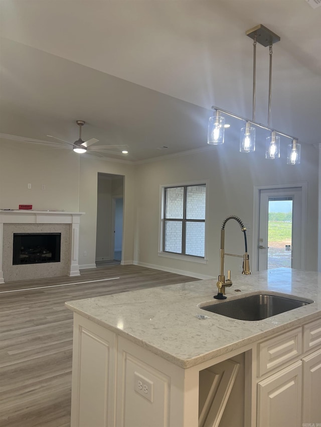 kitchen featuring light stone counters, pendant lighting, a sink, open floor plan, and light wood-type flooring