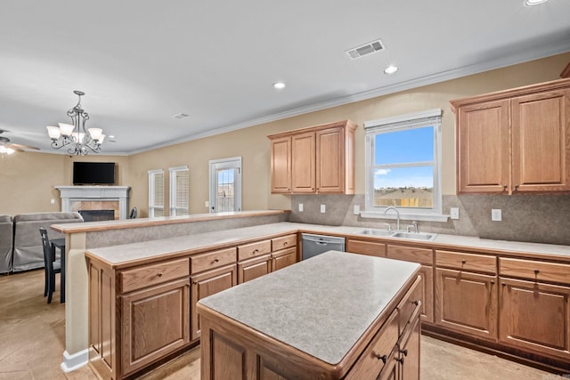 kitchen with sink, dishwasher, a center island, hanging light fixtures, and a tiled fireplace