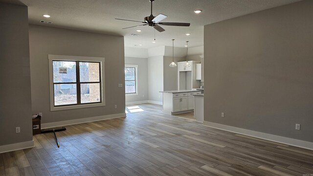 unfurnished living room with recessed lighting, wood finished floors, visible vents, and baseboards