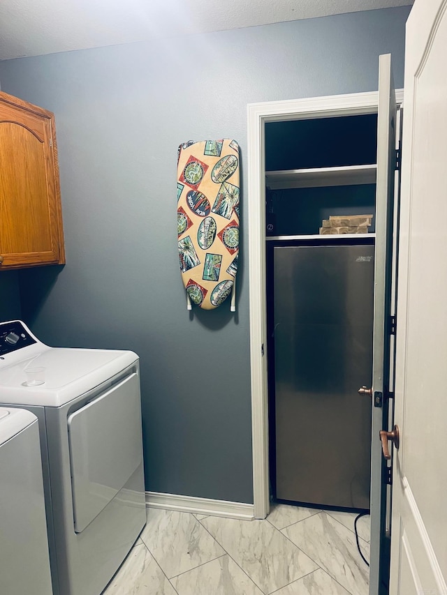 clothes washing area with washing machine and dryer and cabinets