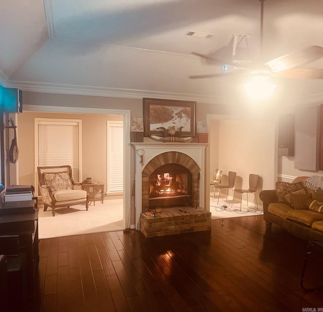 living area featuring vaulted ceiling, dark wood-type flooring, a brick fireplace, and crown molding