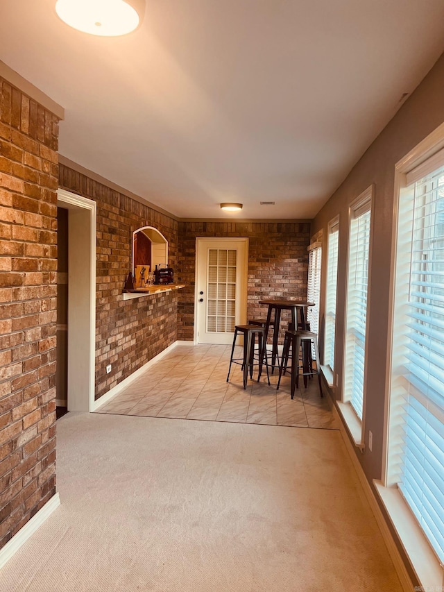 unfurnished dining area featuring carpet flooring and brick wall