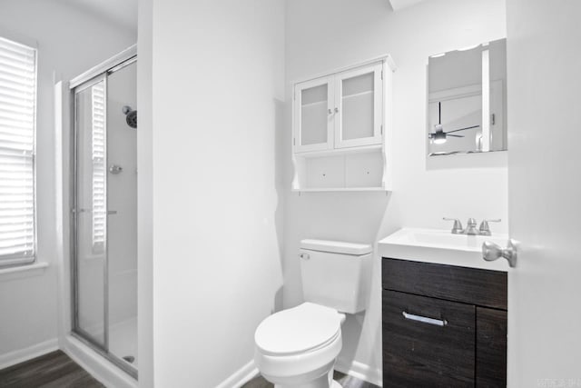 bathroom featuring wood-type flooring, vanity, toilet, and walk in shower