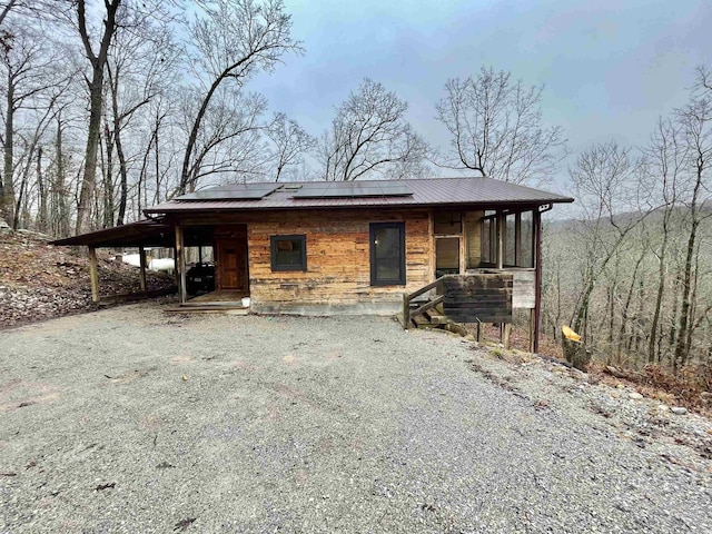 view of front facade featuring a carport, solar panels, and covered porch