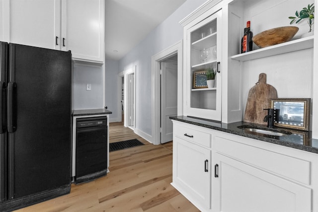 kitchen with black refrigerator, light wood-type flooring, white cabinets, and dark stone countertops