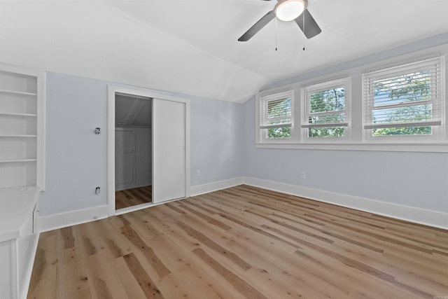 unfurnished bedroom featuring ceiling fan, a closet, lofted ceiling, and light wood-type flooring