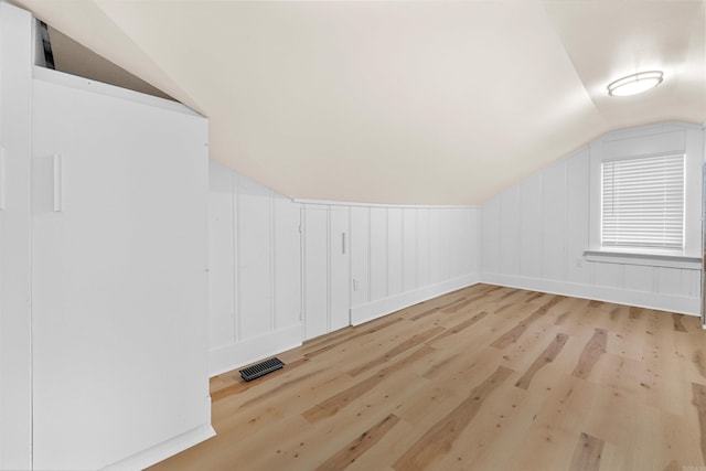 additional living space featuring light wood-type flooring and lofted ceiling