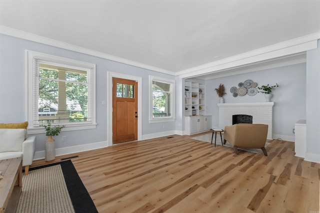 interior space featuring built in shelves, crown molding, light hardwood / wood-style flooring, and a brick fireplace