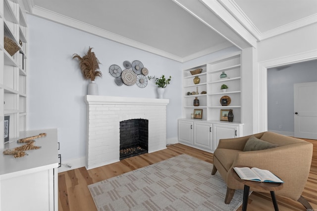 living room featuring crown molding, built in features, light hardwood / wood-style flooring, and a brick fireplace