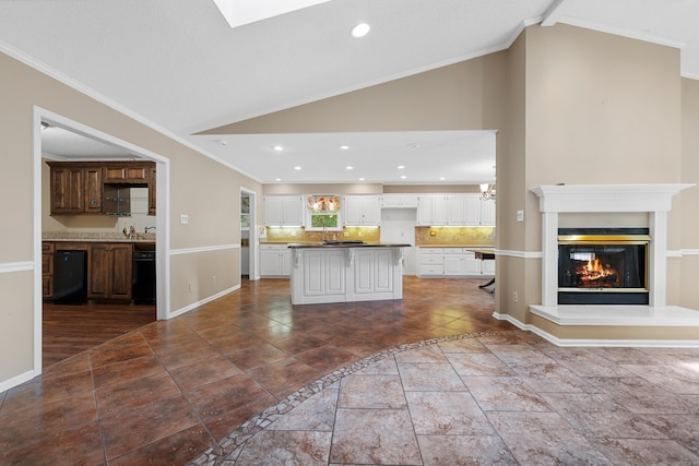 kitchen with backsplash, white cabinets, crown molding, vaulted ceiling, and a kitchen island