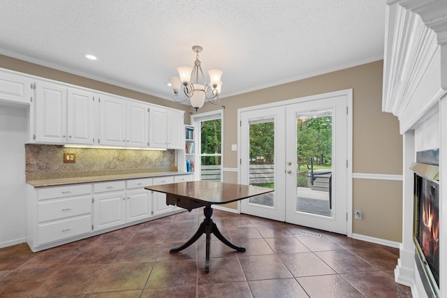 kitchen featuring white cabinetry, french doors, hanging light fixtures, an inviting chandelier, and decorative backsplash