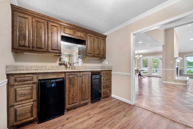 kitchen featuring french doors, a chandelier, a textured ceiling, light wood-type flooring, and ornamental molding