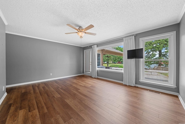 empty room featuring ceiling fan, wood-type flooring, a textured ceiling, and ornamental molding