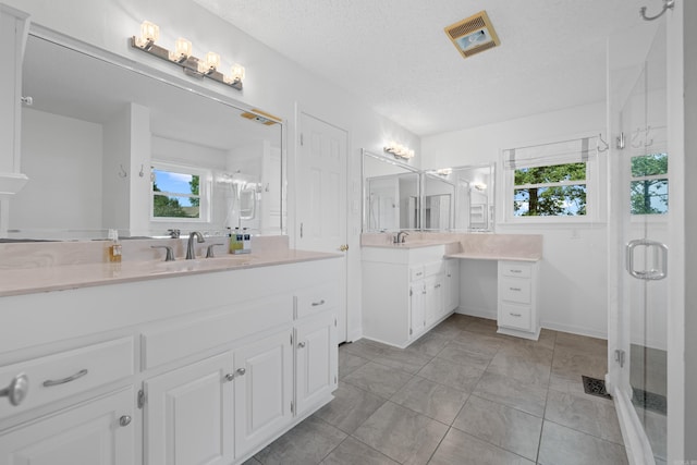 bathroom featuring vanity, a textured ceiling, tile patterned floors, and a shower with shower door