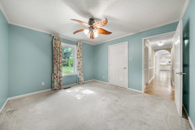 unfurnished bedroom with a textured ceiling, ceiling fan, light colored carpet, and crown molding