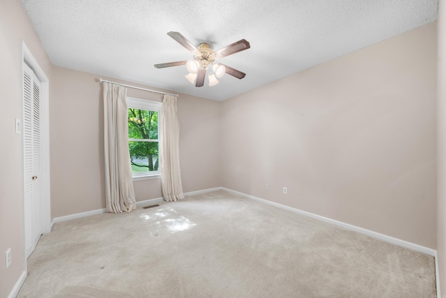 carpeted empty room with ceiling fan and a textured ceiling