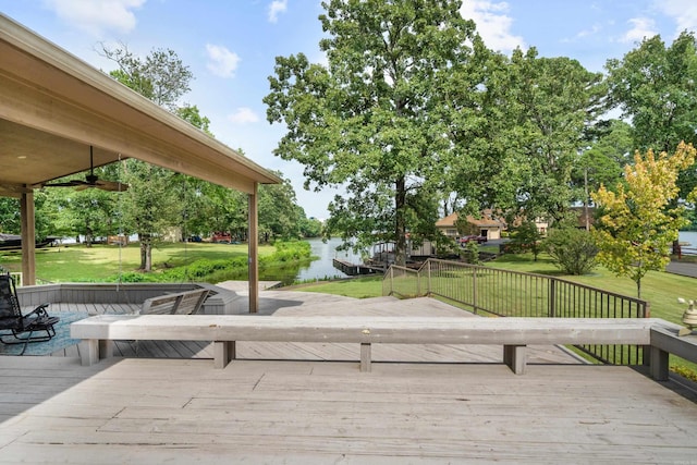 deck featuring a lawn, ceiling fan, and a water view