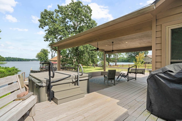 wooden deck featuring ceiling fan, area for grilling, and a water view