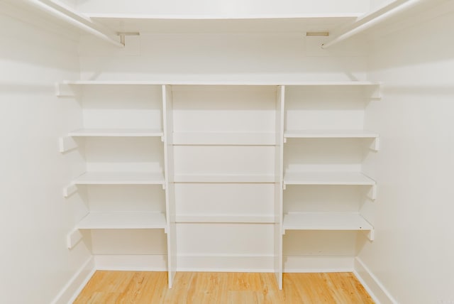 walk in closet with hardwood / wood-style flooring