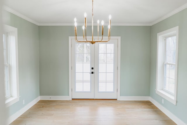 entryway featuring plenty of natural light, light hardwood / wood-style flooring, crown molding, and a chandelier