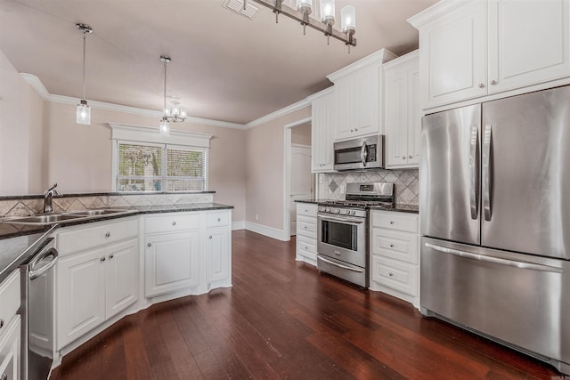 kitchen featuring pendant lighting, stainless steel appliances, sink, and white cabinets