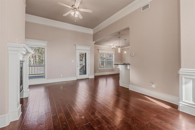 unfurnished living room featuring dark hardwood / wood-style flooring, ornamental molding, and ceiling fan