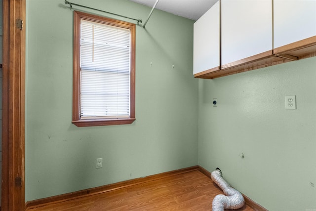 laundry area featuring cabinets, light hardwood / wood-style flooring, a wealth of natural light, and electric dryer hookup