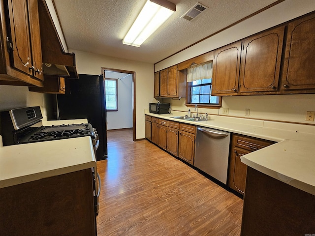 kitchen featuring white gas stove, sink, stainless steel dishwasher, and plenty of natural light