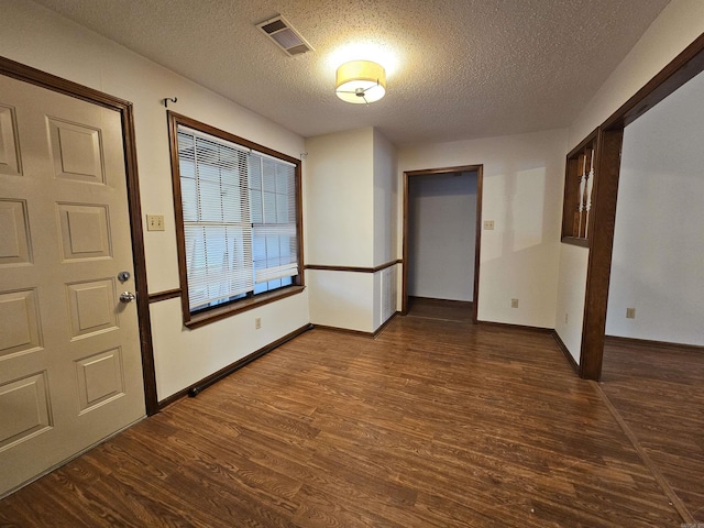 foyer entrance with a textured ceiling and dark wood-type flooring