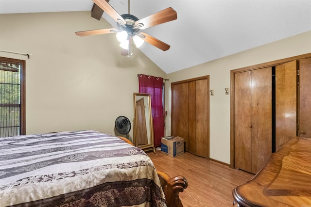 bedroom with light wood-type flooring, two closets, ceiling fan, and lofted ceiling