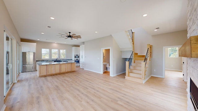 kitchen featuring ceiling fan, white cabinetry, light hardwood / wood-style flooring, a kitchen island, and appliances with stainless steel finishes