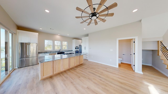 kitchen with white cabinetry, light stone countertops, light wood-type flooring, and appliances with stainless steel finishes