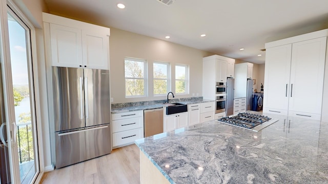 kitchen with white cabinets, light stone counters, sink, and appliances with stainless steel finishes