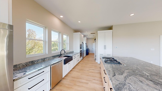 kitchen with white cabinetry, sink, appliances with stainless steel finishes, and dark stone counters