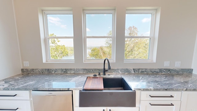 kitchen with dishwasher, light stone counters, white cabinetry, and sink