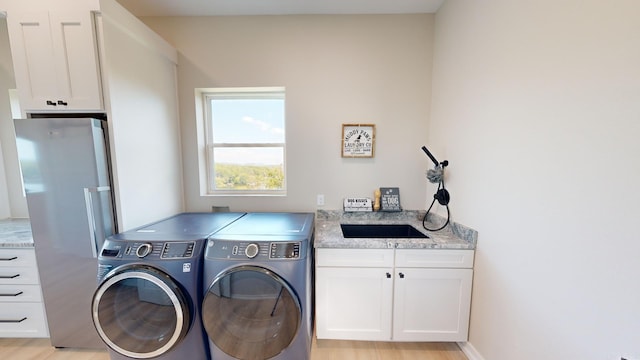 laundry area featuring cabinets, separate washer and dryer, and light hardwood / wood-style flooring