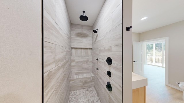 bathroom with a tile shower and toilet