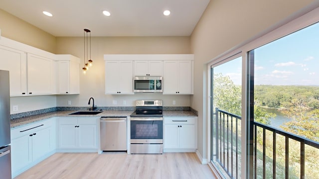 kitchen featuring white cabinetry, sink, hanging light fixtures, light hardwood / wood-style flooring, and appliances with stainless steel finishes