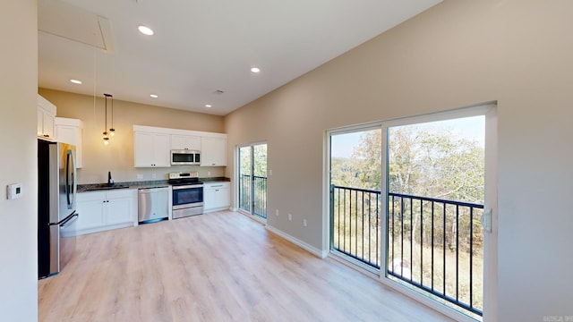 kitchen featuring sink, light wood-type flooring, decorative light fixtures, white cabinetry, and stainless steel appliances