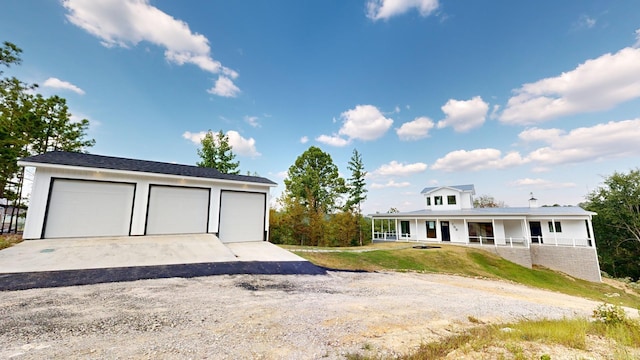 view of front of home with a porch, a garage, a front lawn, and an outdoor structure