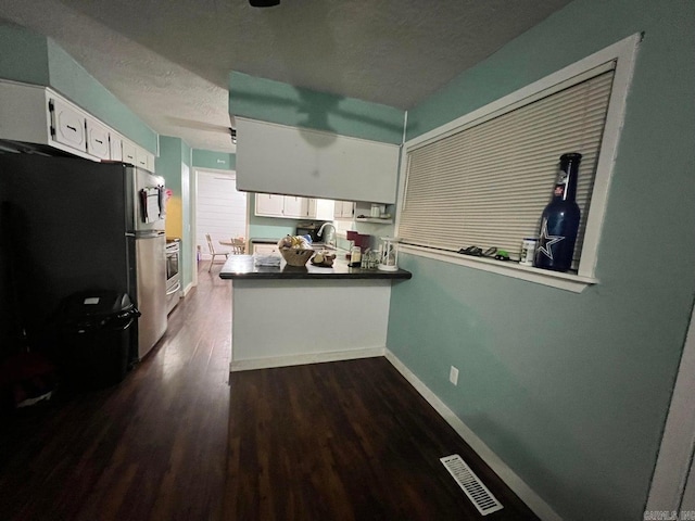 kitchen featuring sink, wall oven, stainless steel fridge, a textured ceiling, and white cabinets