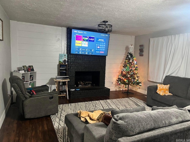 living room with a textured ceiling, hardwood / wood-style flooring, and a large fireplace